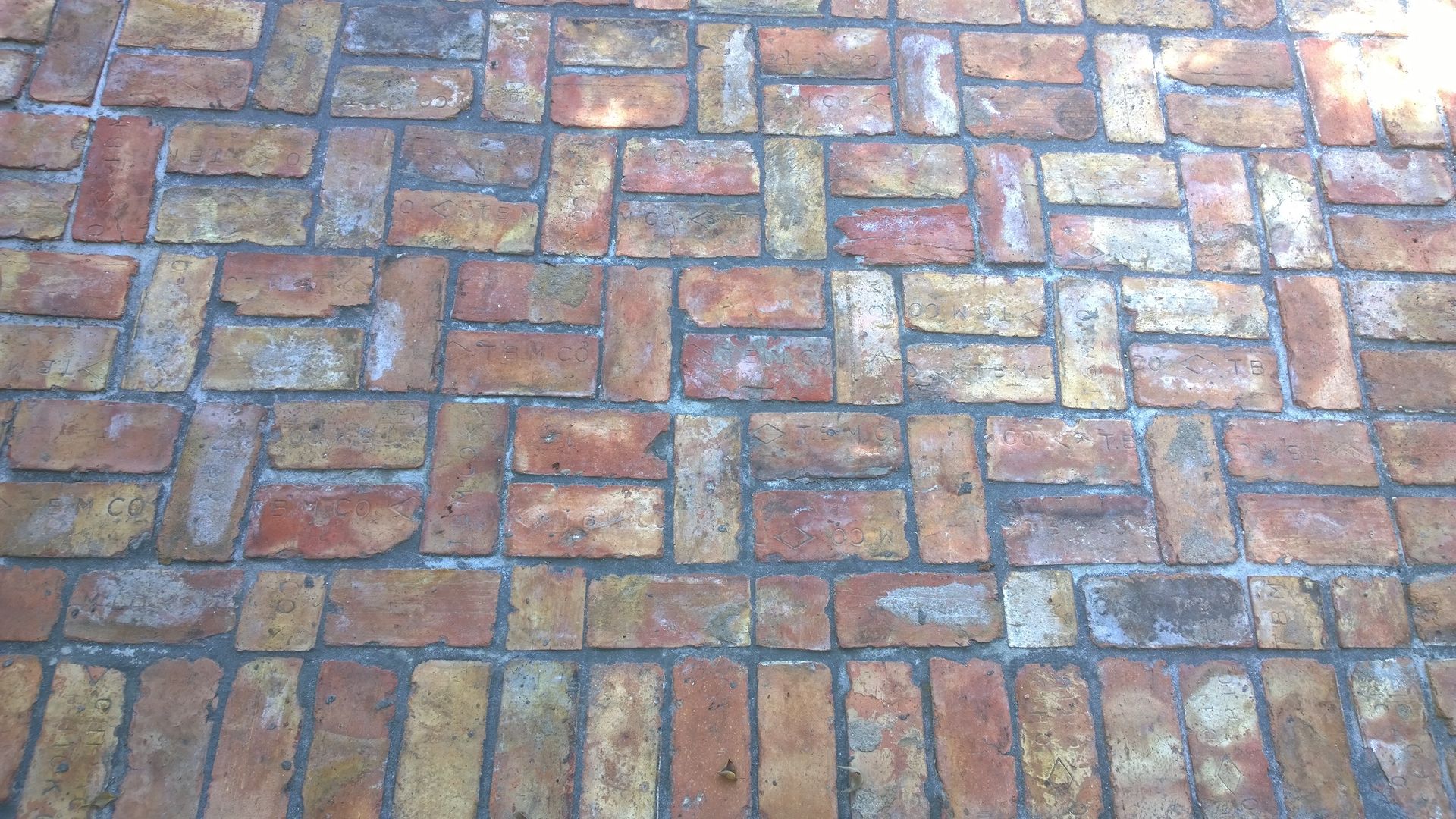 Wet multicolored brick pavement with blue-gray mortar lines