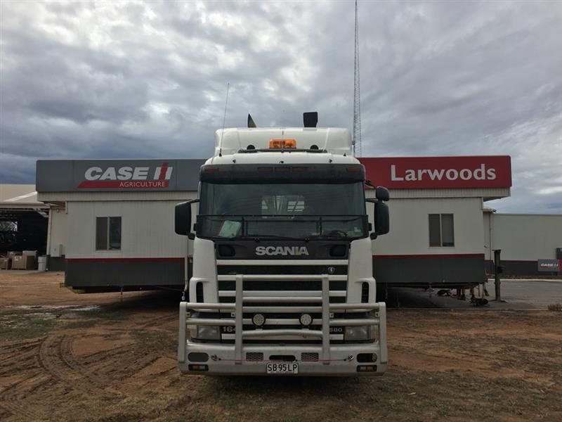 White Scania truck parked in front of Larwoods and Case IH buildings under a cloudy sky White Scania truck parked in front of Larwoods and Case IH buildings under a cloudy sky