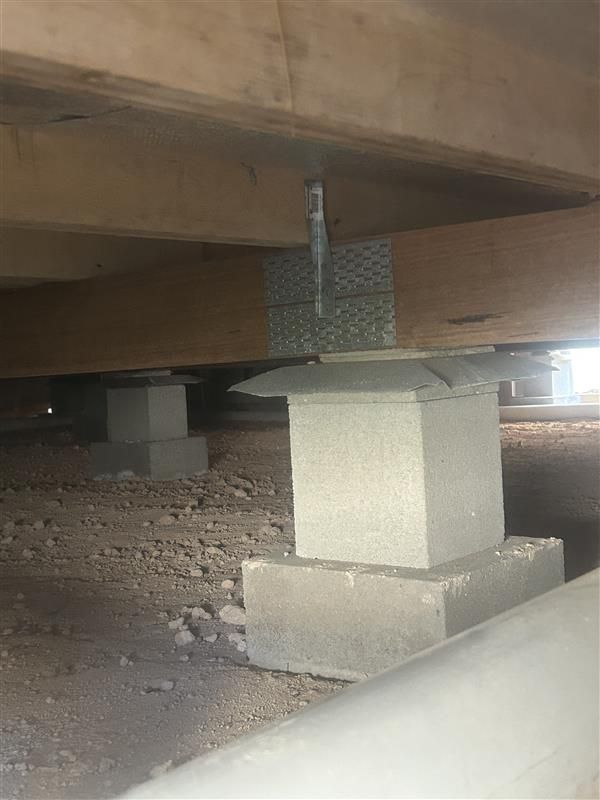 Underfloor concrete supports and a metal bracket beneath a wooden structure Underfloor concrete supports and a metal bracket beneath a wooden structure