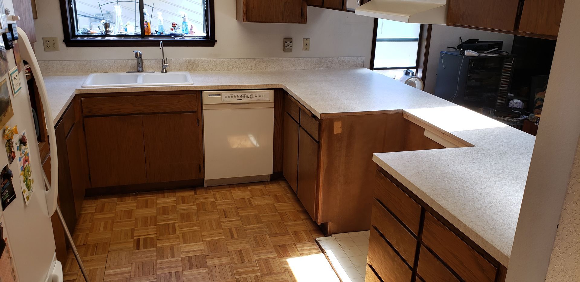 Kitchen with brown cabinets, white countertops, white appliances, and wood flooring.
