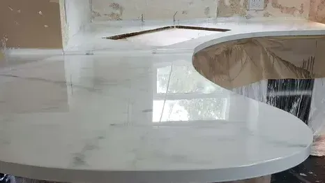 White marble countertop with glossy finish, curved edge.