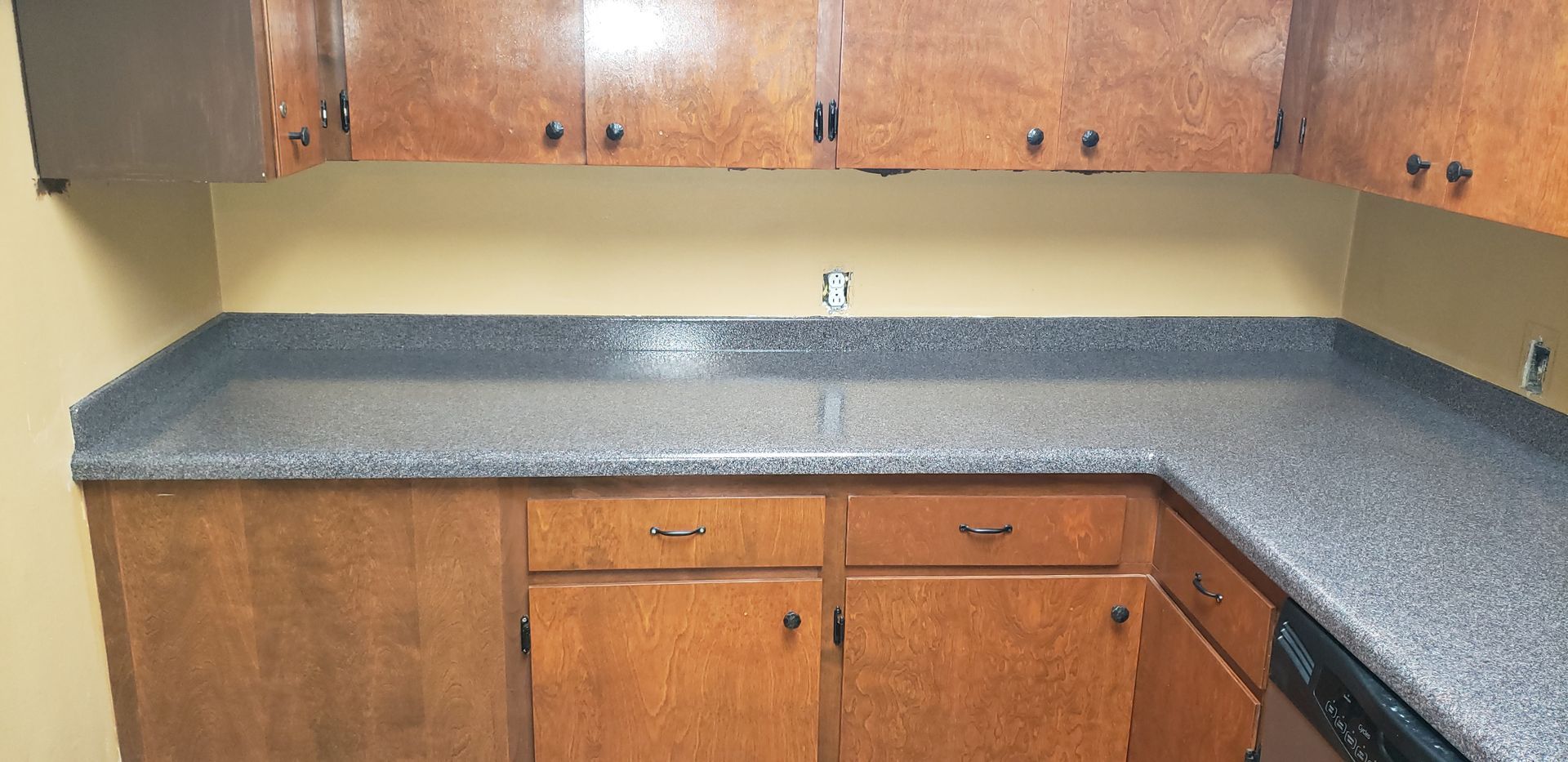 Kitchen with wooden cabinets and dark speckled countertops.