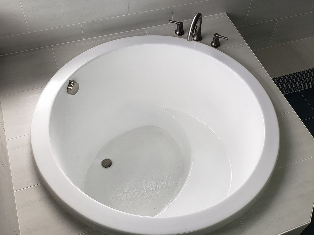 White, round bathtub with silver fixtures in a bathroom.