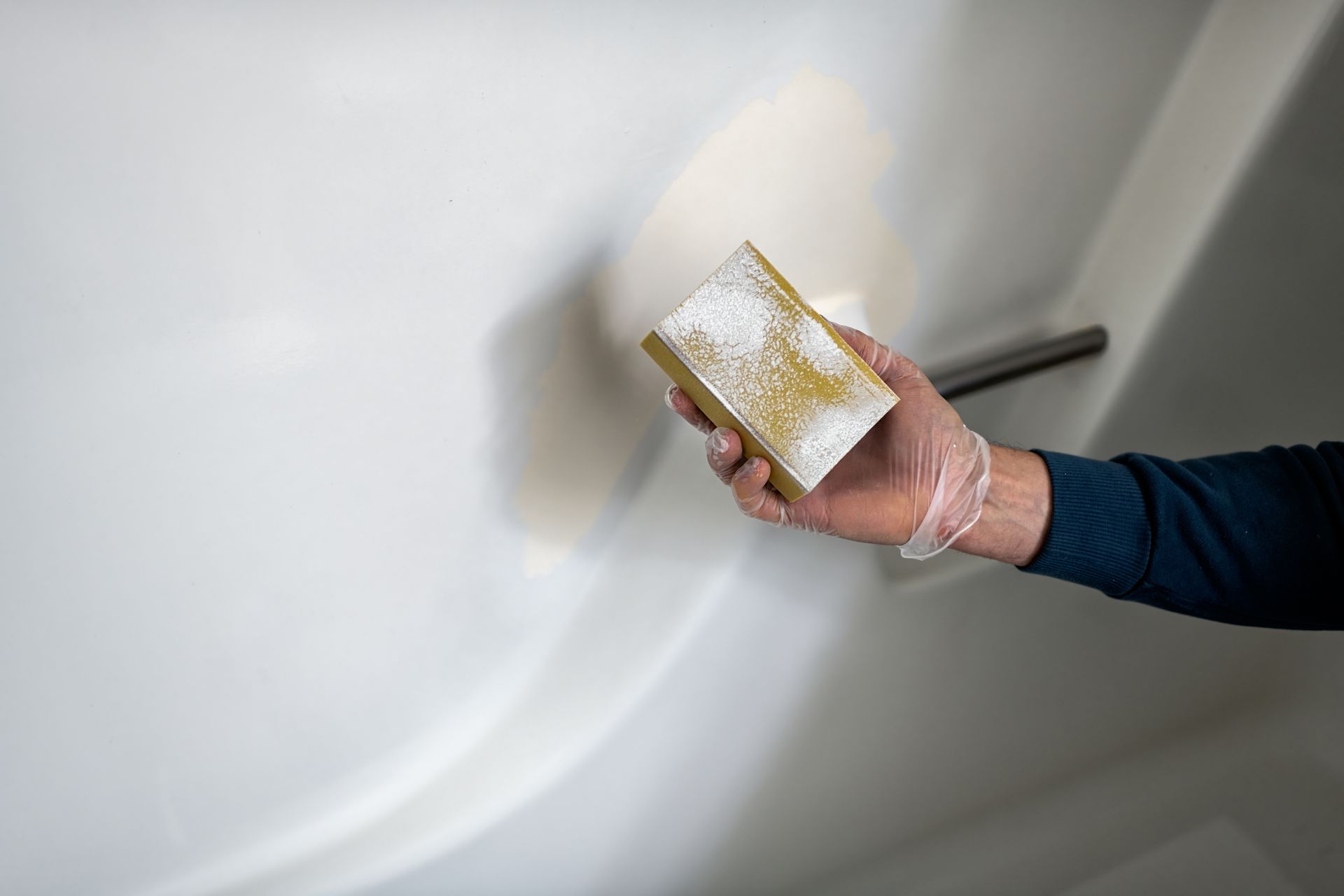 Hand sanding a patched wall with a sanding block for a smooth finish. ] 