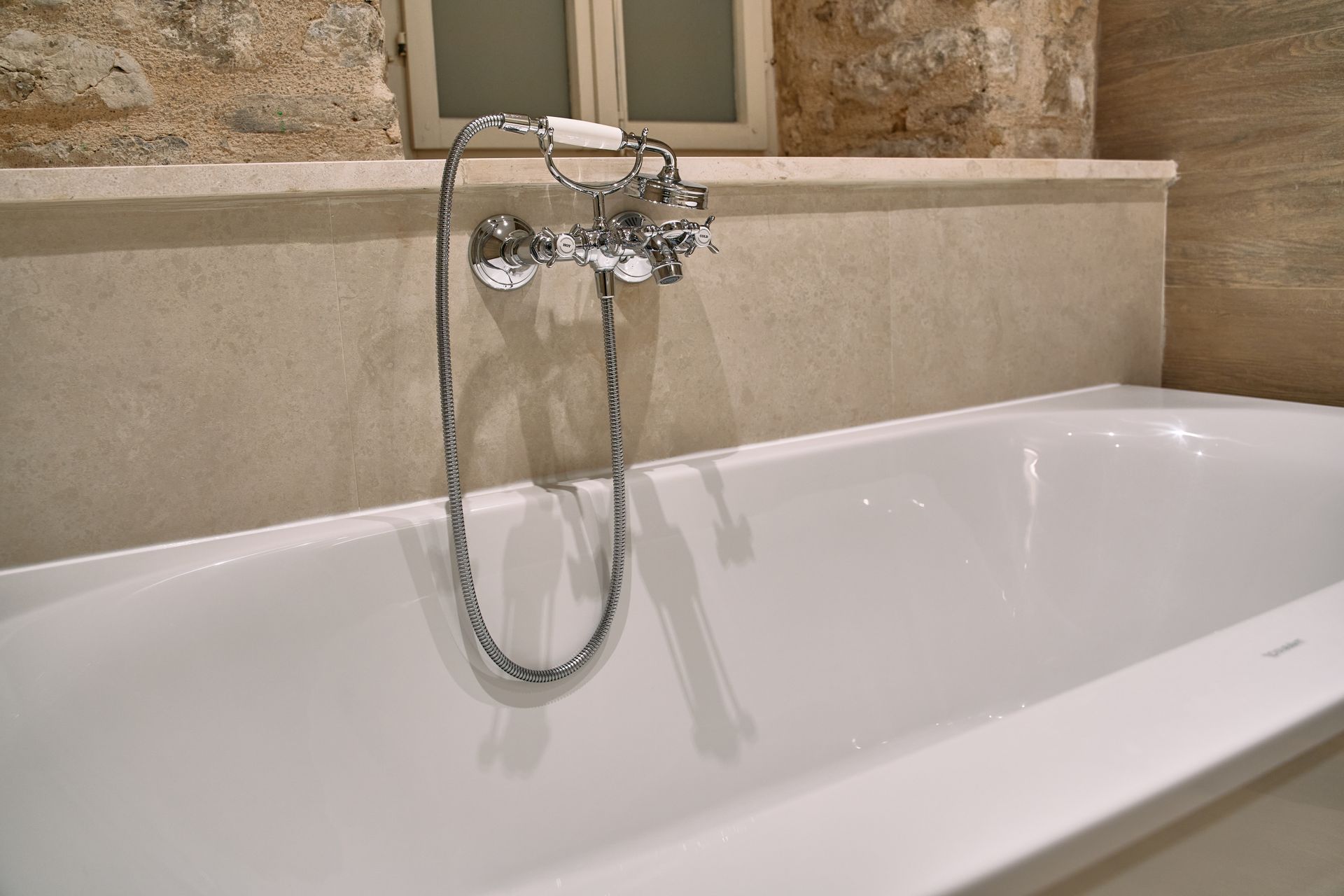 Clean white bathtub with chrome faucet in a modern bathroom setting.