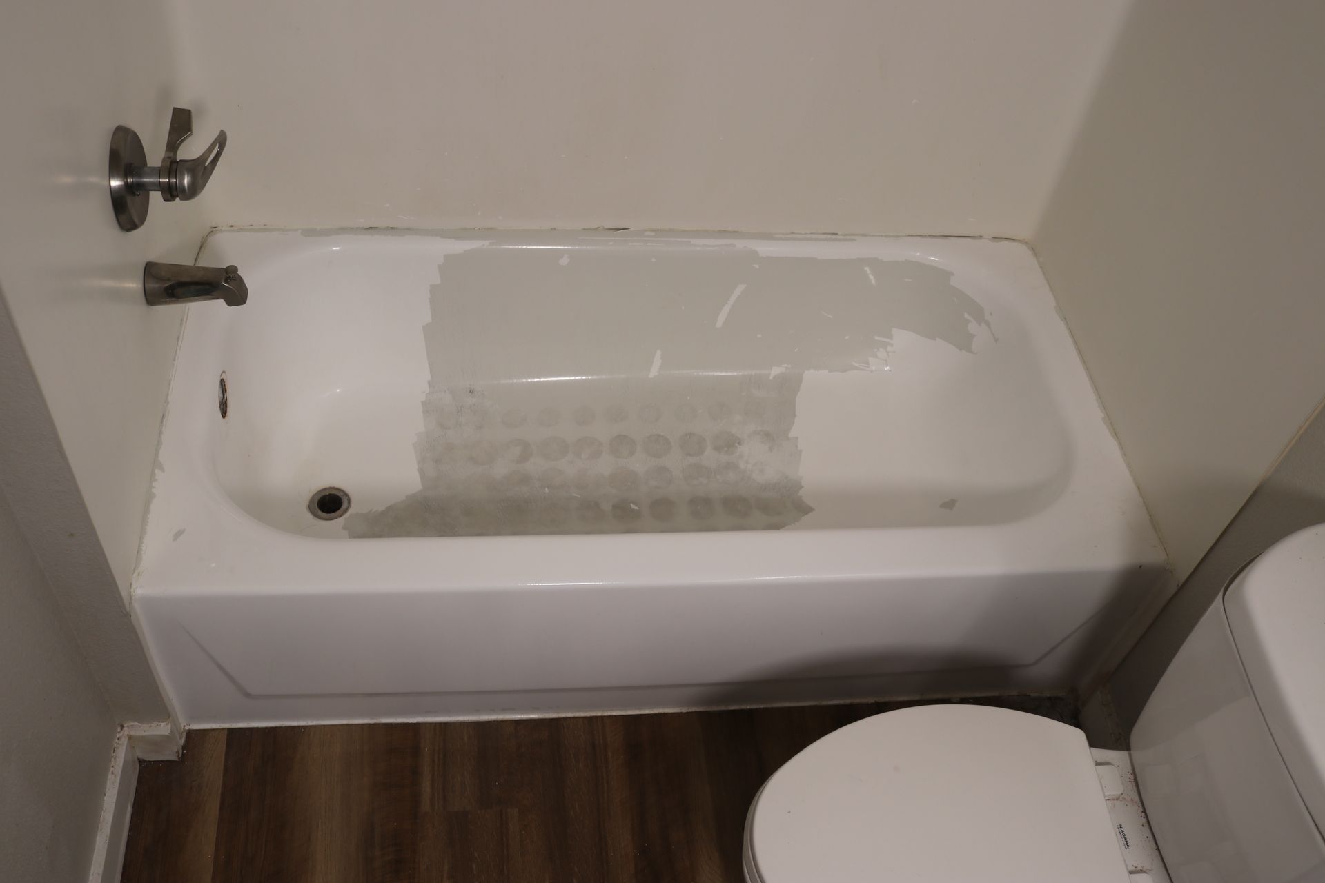 White bathtub with faucet and toilet in a bathroom.
