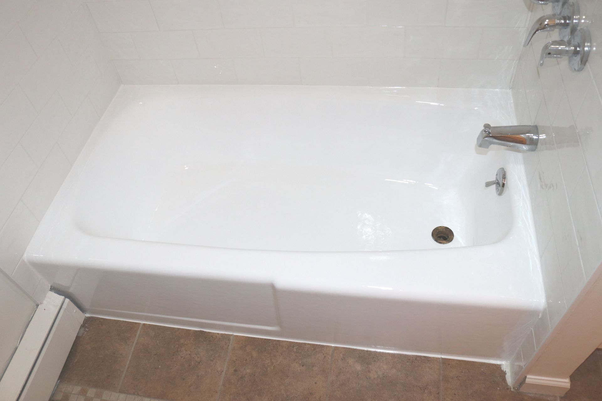 White bathtub in a tiled bathroom, viewed from above.