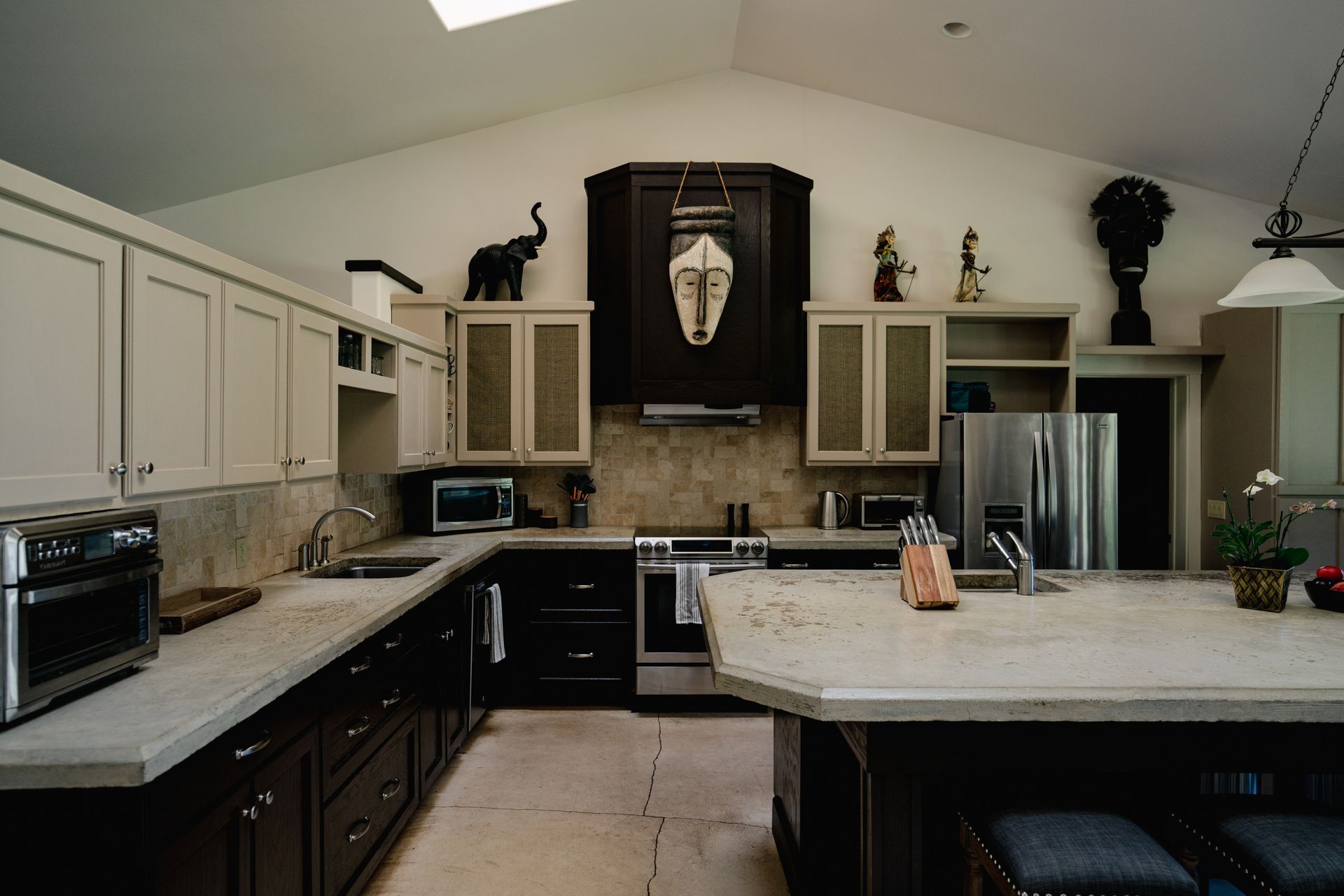 U-shaped kitchen with dark and light cabinets, granite counters, and decorative elephant statues.