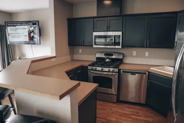 Kitchen with dark blue cabinets, stainless steel appliances, and beige countertops.