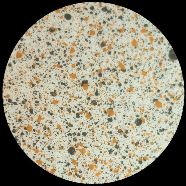 Circle with white, black, and orange speckled pattern, resembling a speckled terrazzo design.