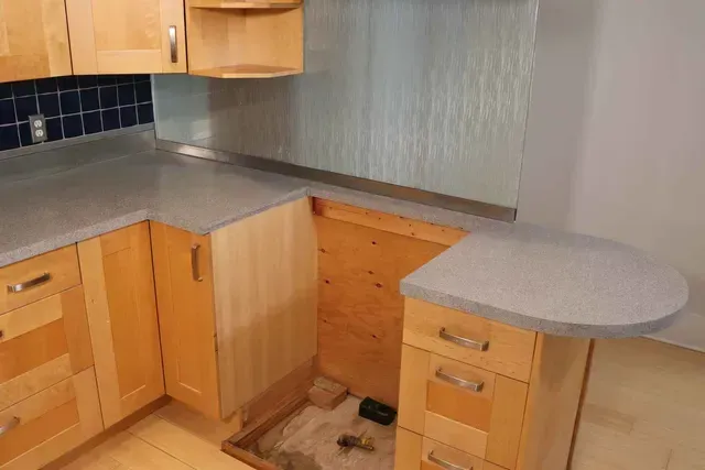 Kitchen with light wood cabinets, gray countertops, and a partially built-in peninsula.