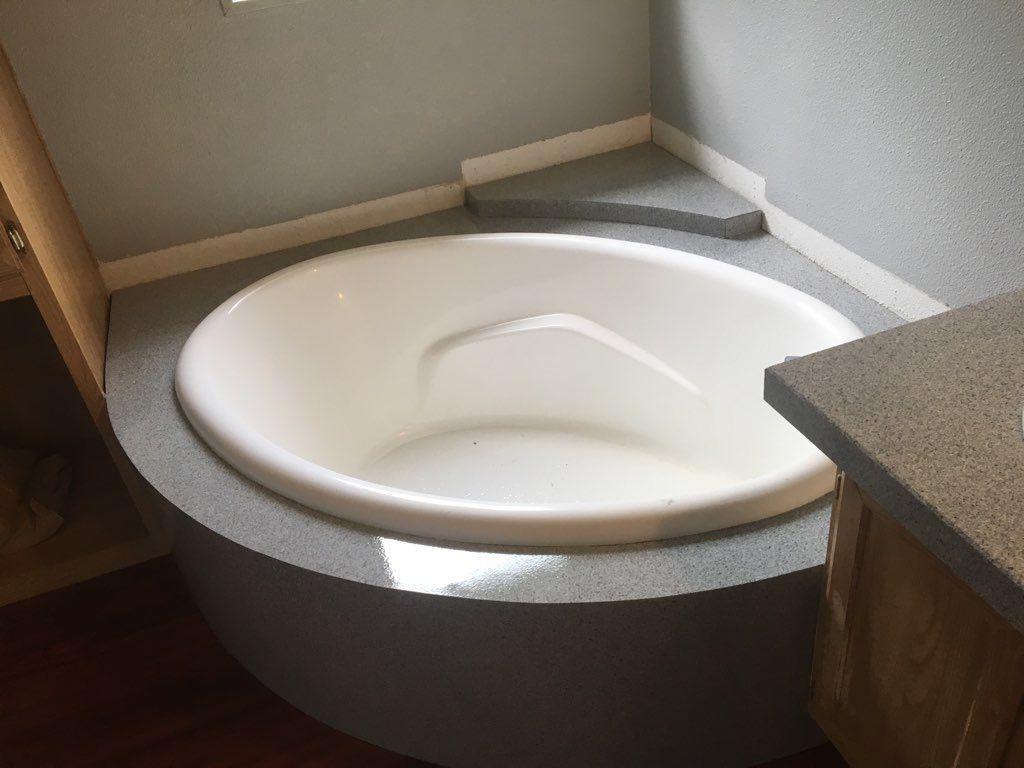 Round white bathtub in a gray-walled corner. Gray countertop extends from the right.