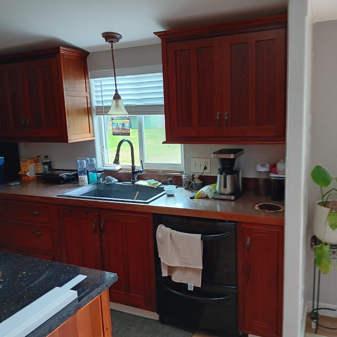 Kitchen with dark wood cabinets, black sink, and window above.