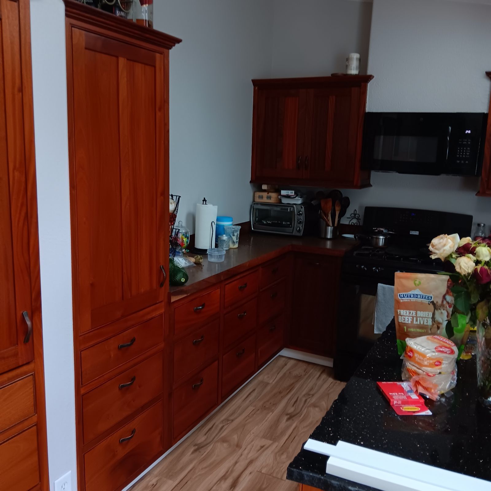 Kitchen with dark wood cabinets, black countertops, and appliances.