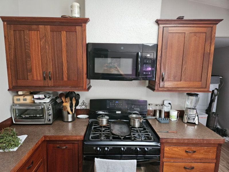 Kitchen with dark wood cabinets, black appliances, and a countertop, items on the countertop.