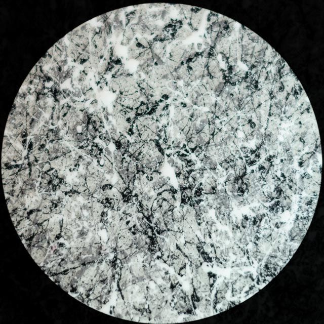 Circular marble pattern with white, gray, and black veins.
