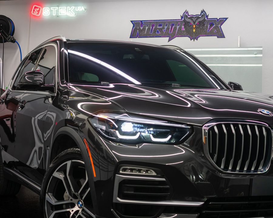 Glossy black SUV side view with tinted windows and chrome trim in a showroom