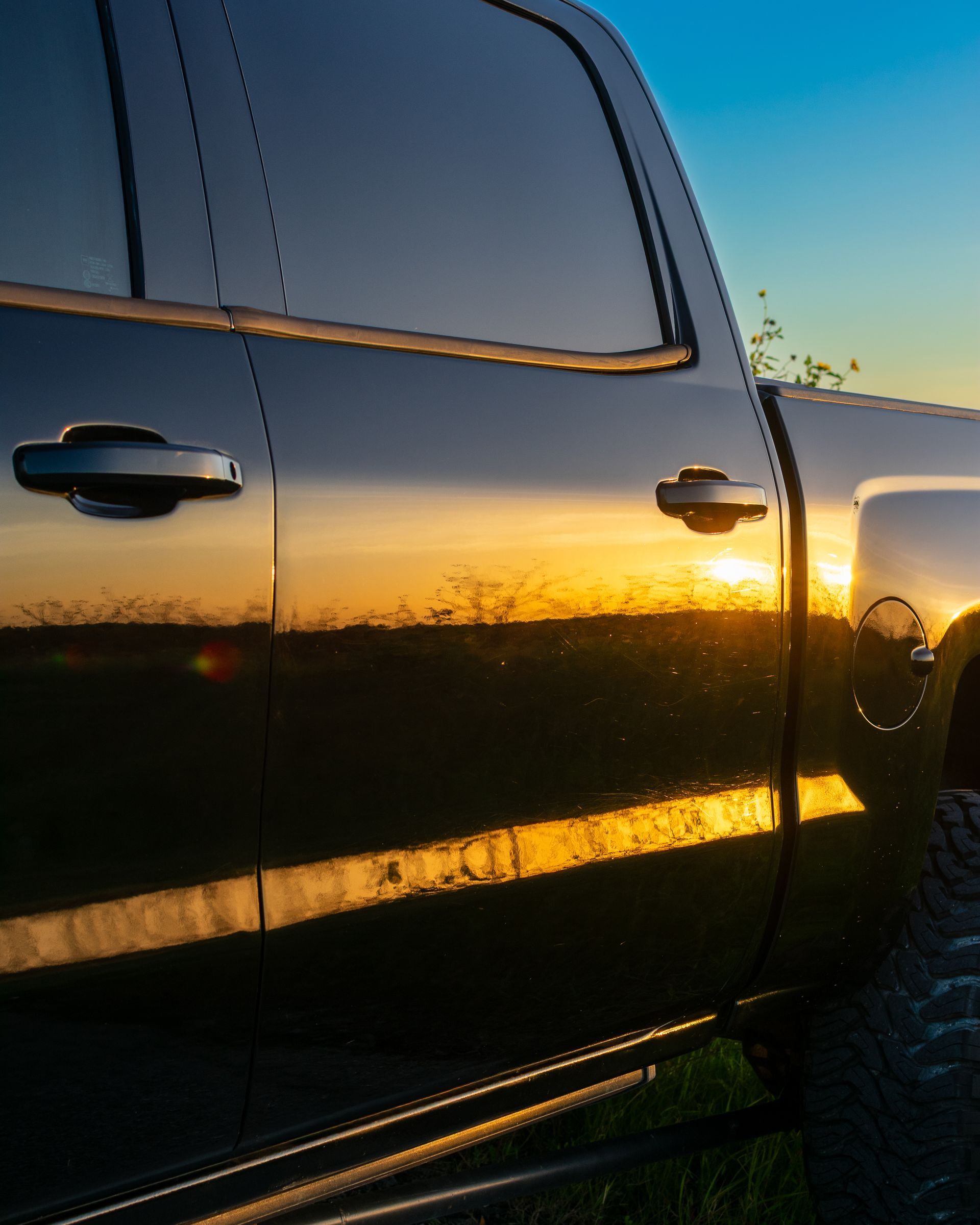 Black pickup truck side in sunset light with reflections on glossy doors and windows