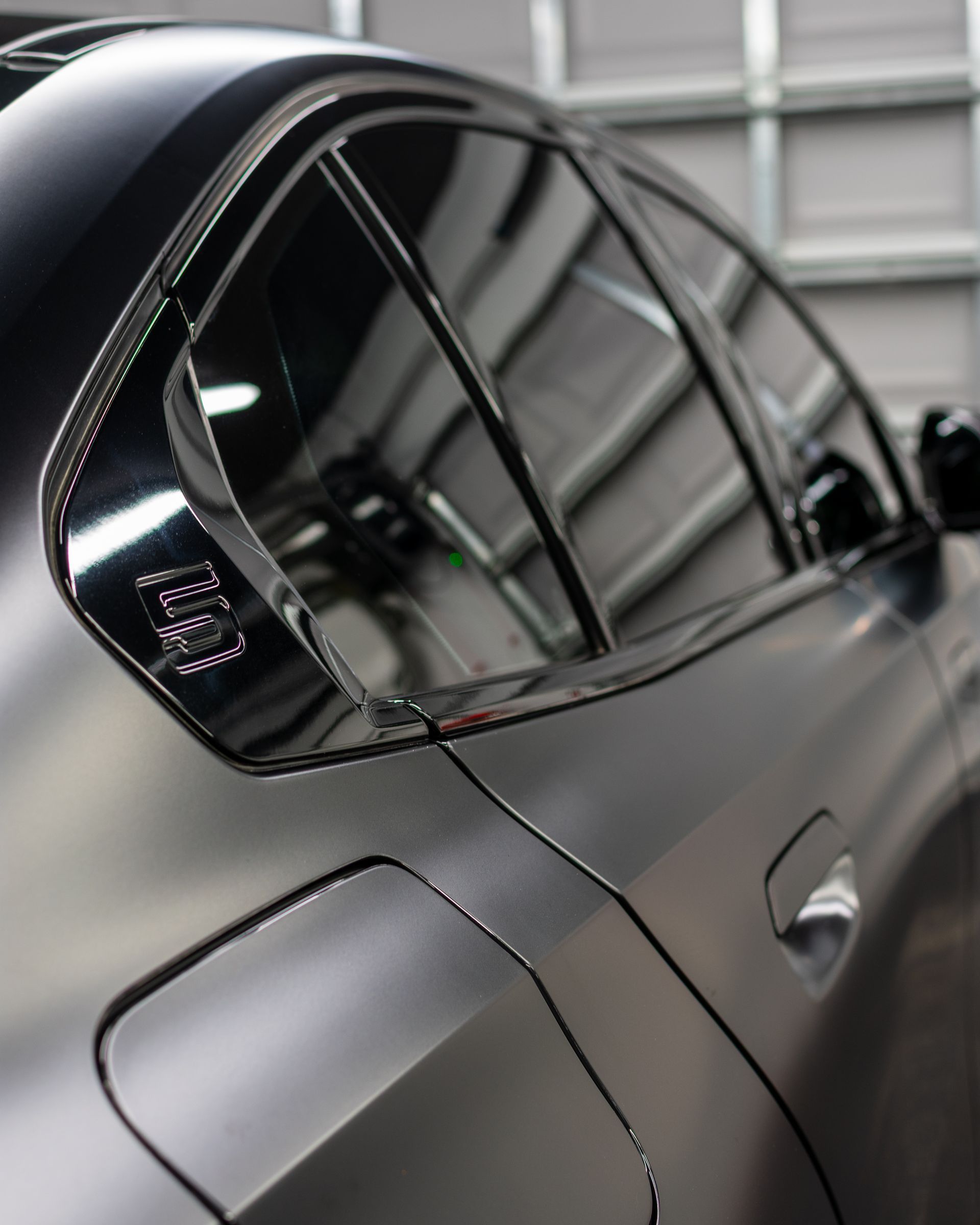 Worker polishing a white car window in an auto detailing shop