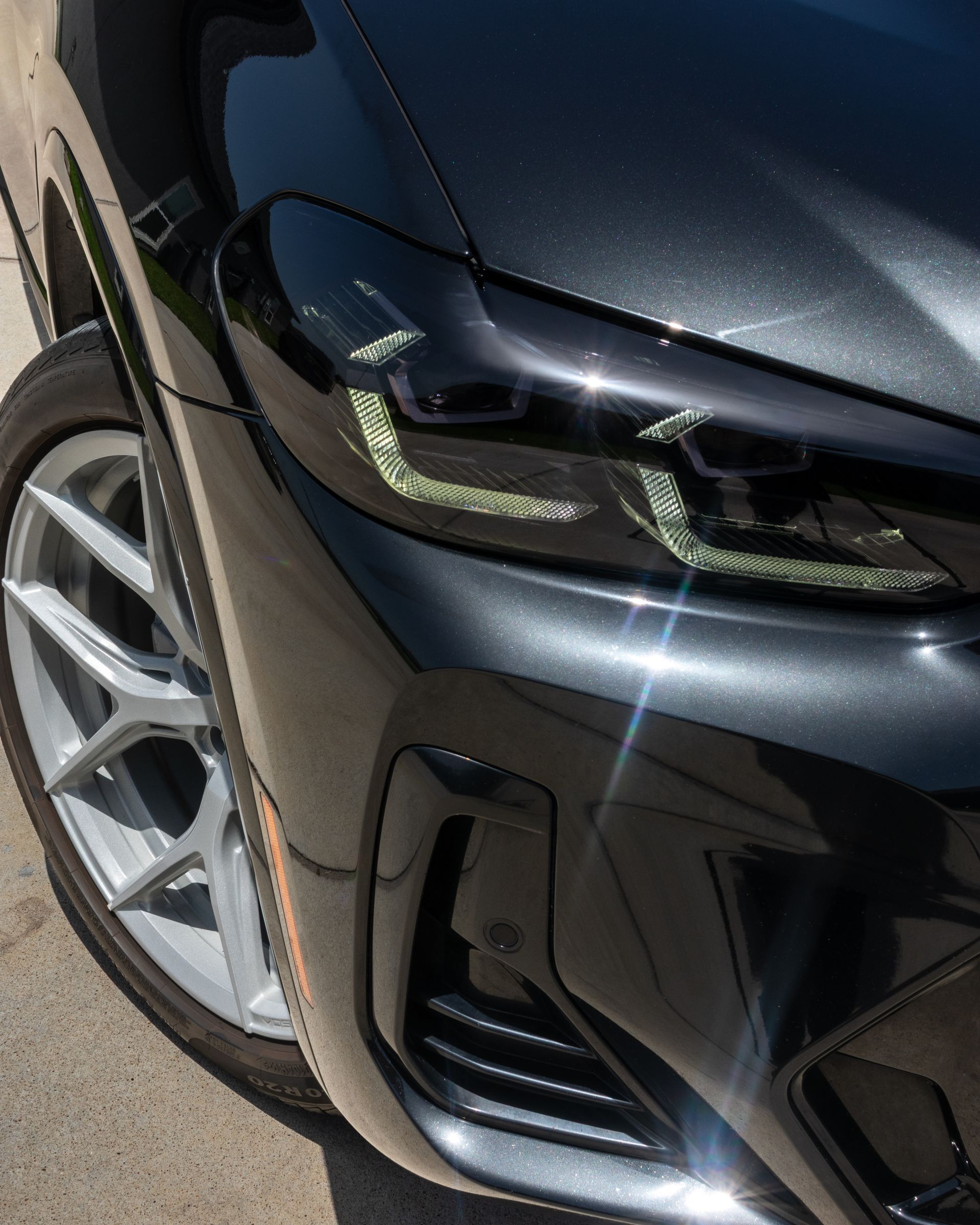 Gloved hands polishing a dark car panel with a buffer, creating a glossy finish.