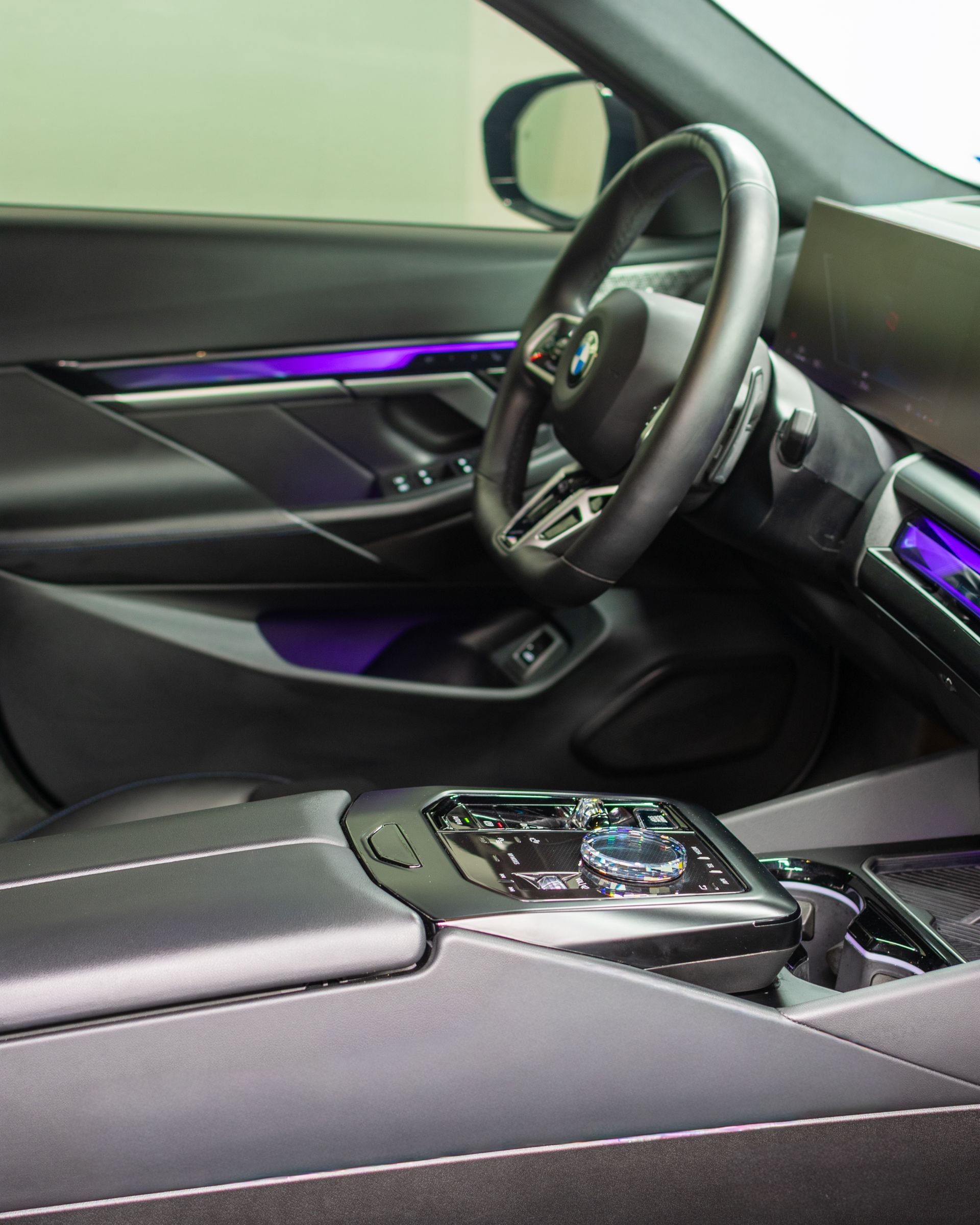 Car interior with purple ambient lighting, steering wheel, and center console in a modern car.