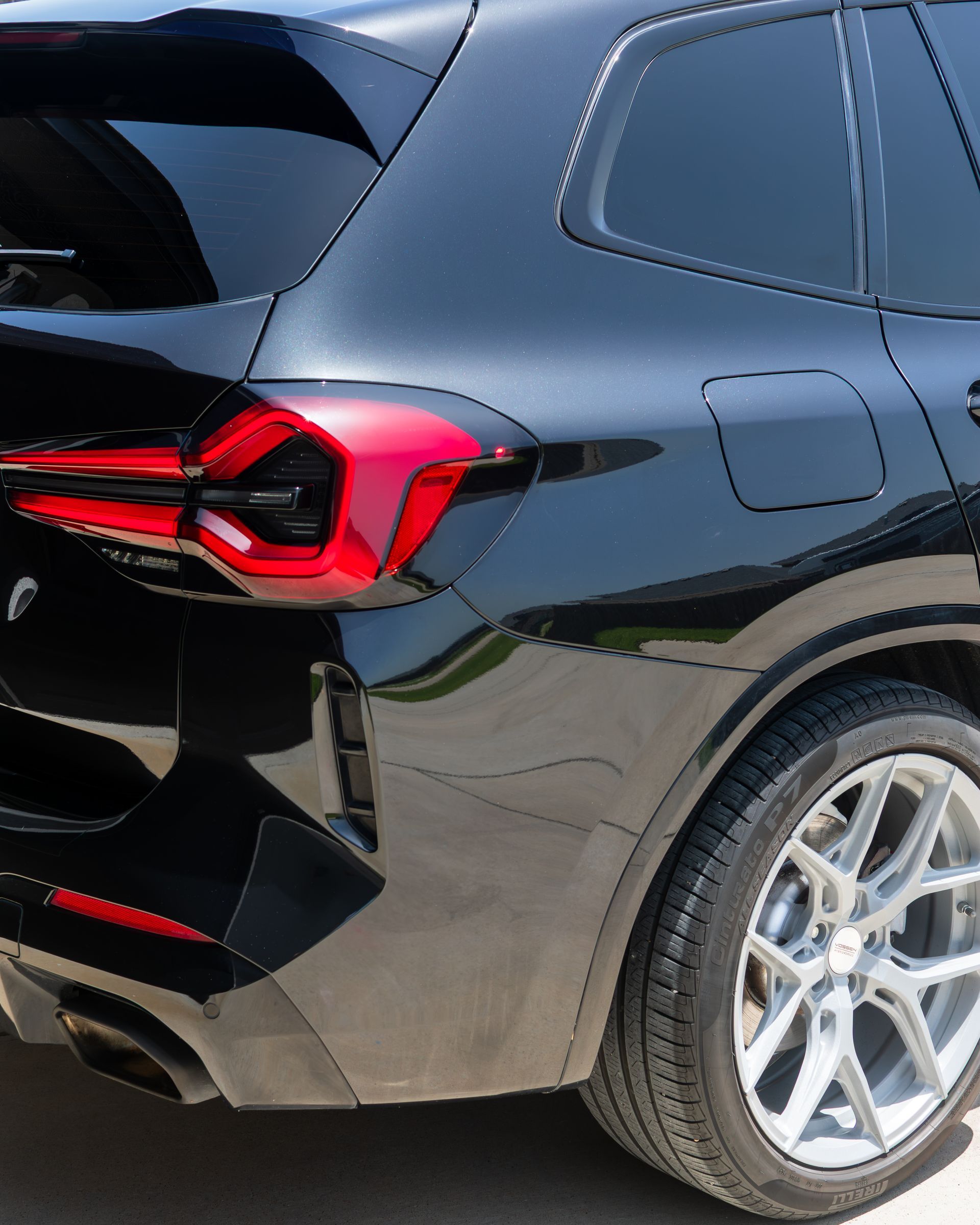 Black SUV rear side with tinted windows, red taillight, and silver wheel parked outdoors