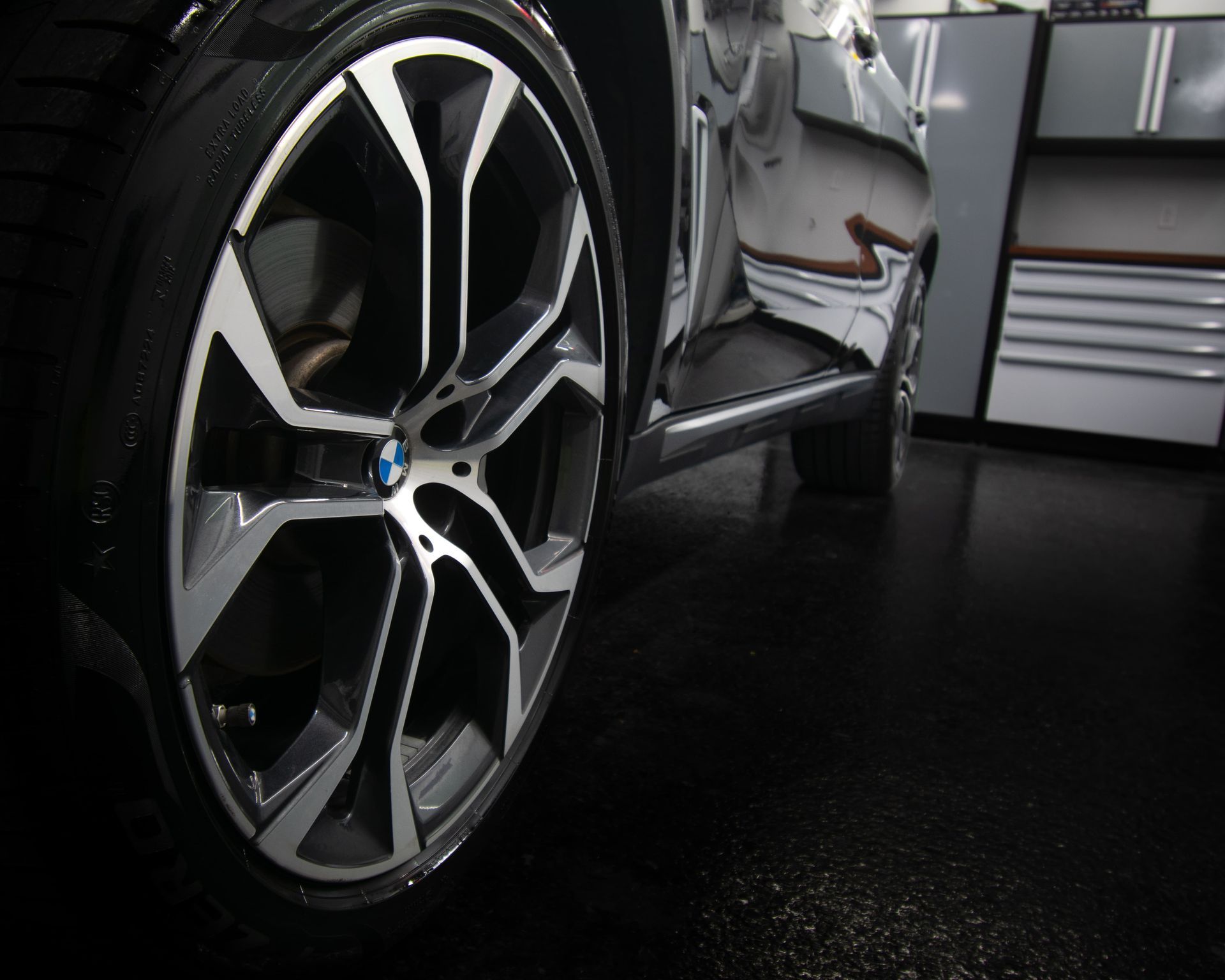 Close-up of a silver car wheel and tire on a dark garage floor
