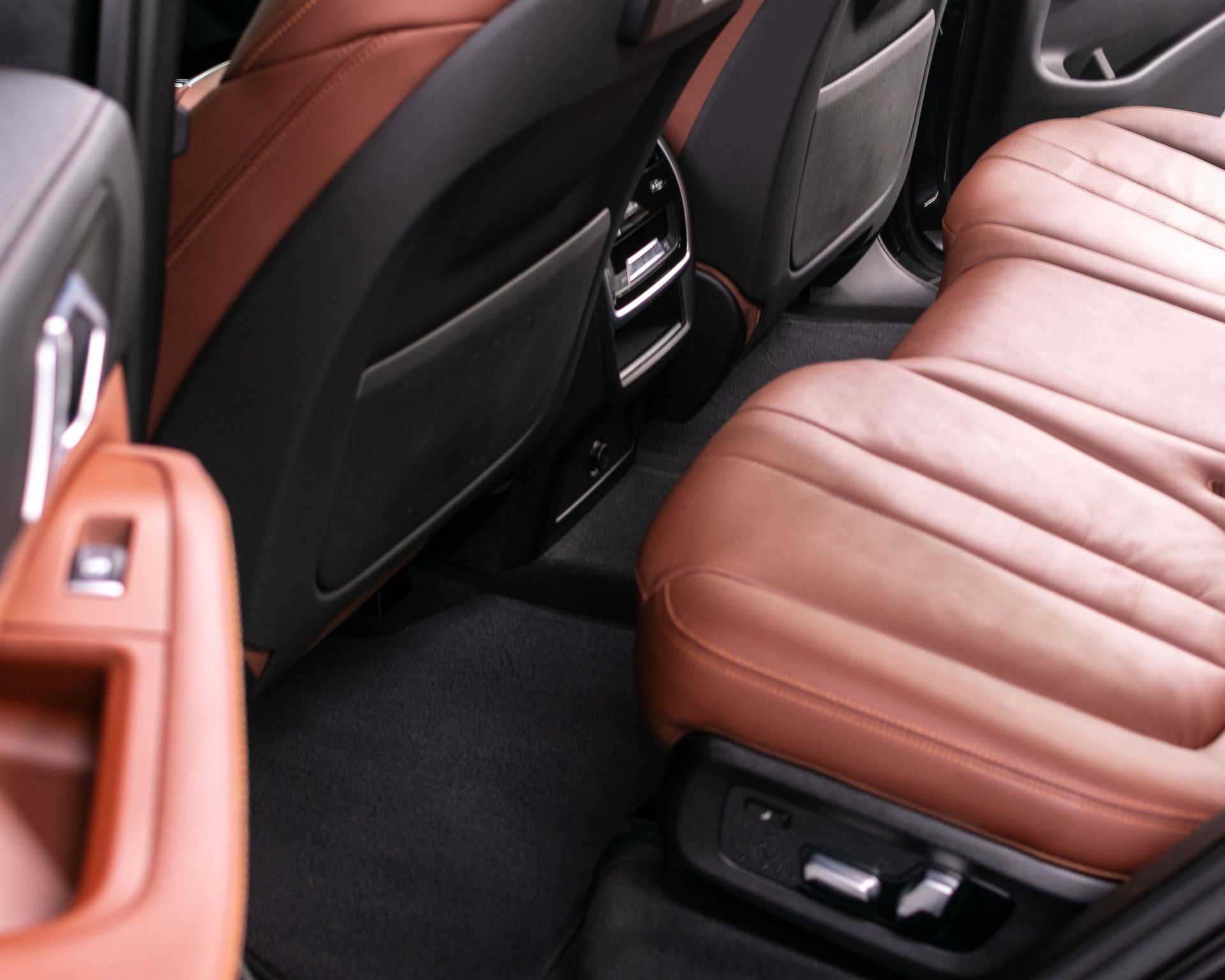 Hand cleaning a car dashboard with a blue cloth inside a brown interior.