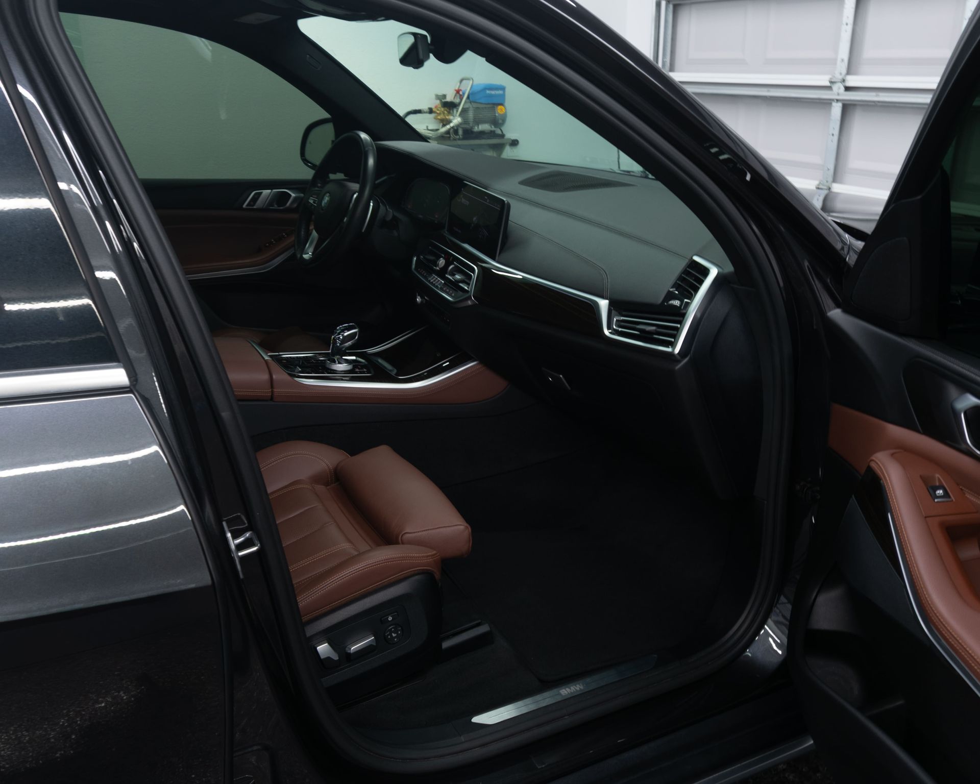 Car interior with brown leather seats and a black floor mat, viewed from the rear passenger side