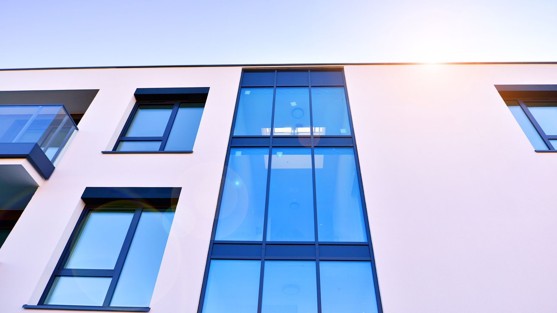 Modern apartment building facade with blue-tinted windows and white exterior walls
