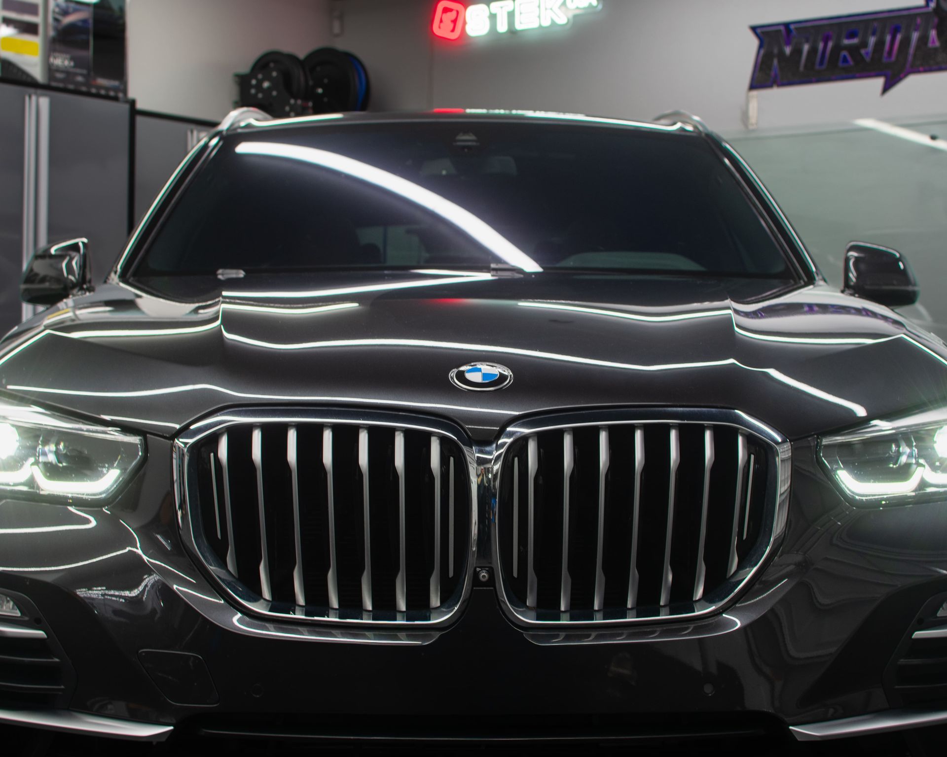 Front view of a black BMW sedan with headlights on in an indoor showroom