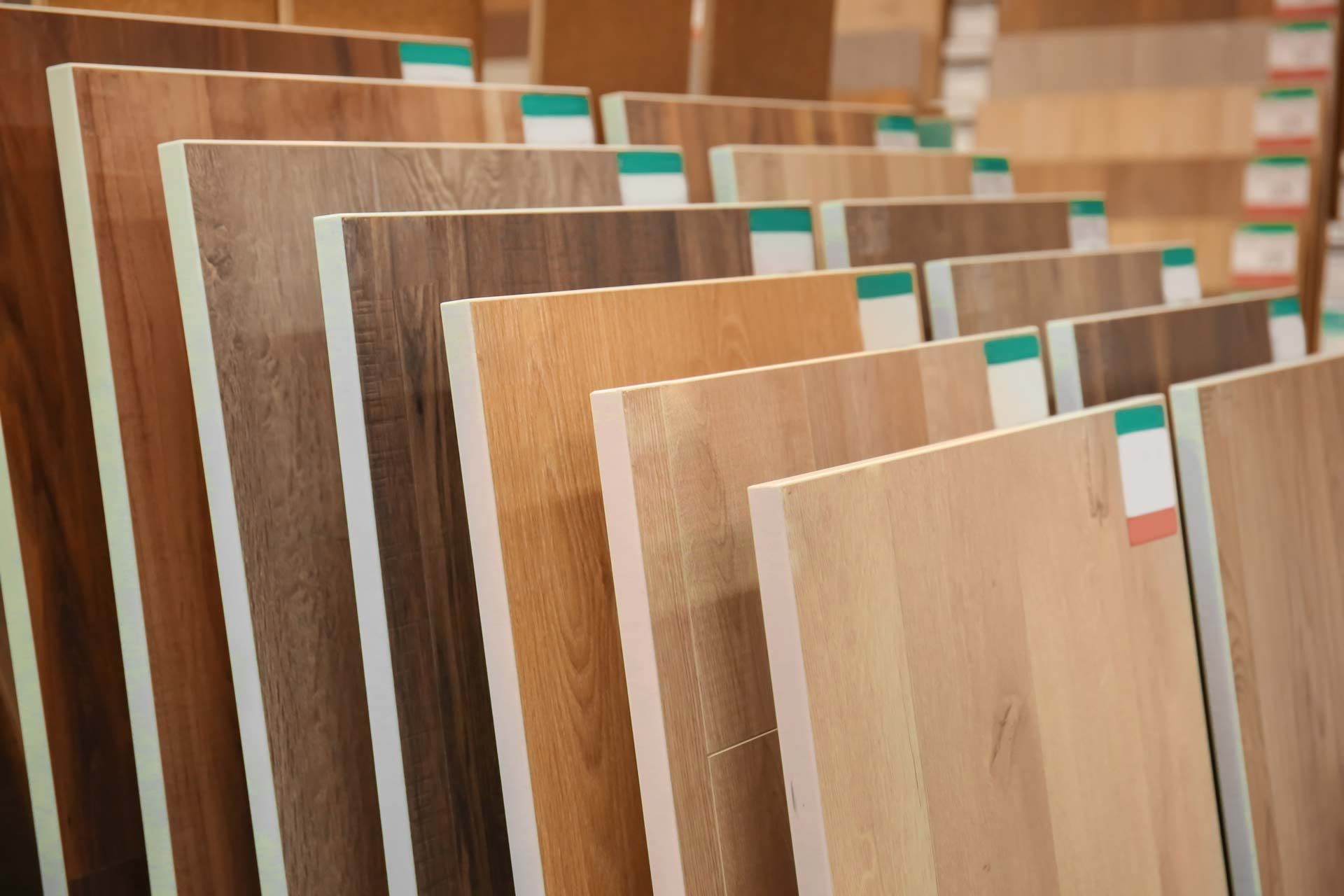 A selection of wood-look laminate flooring samples displayed on a rack in a showroom.