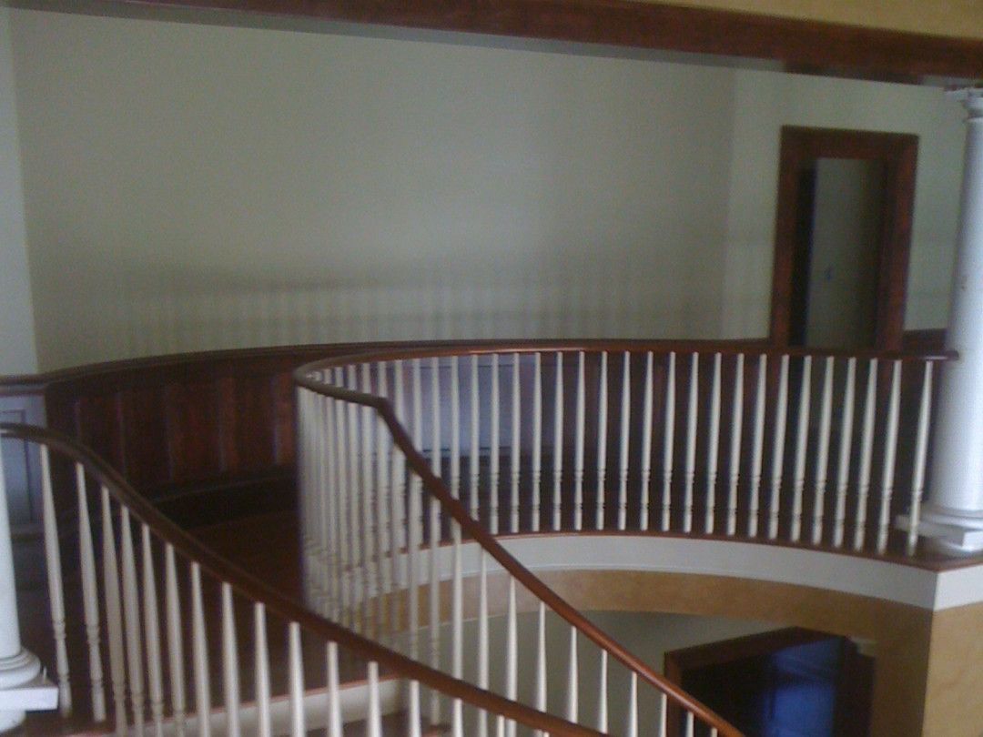 Staircase with curved white railing and dark wood trim in a hallway.