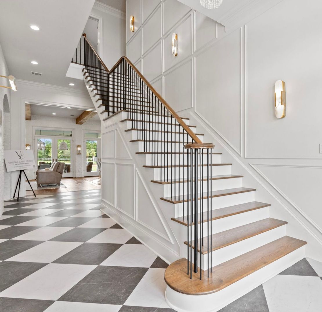 Modern foyer with a black-and-white checkerboard floor and a white staircase with wood steps and black railings