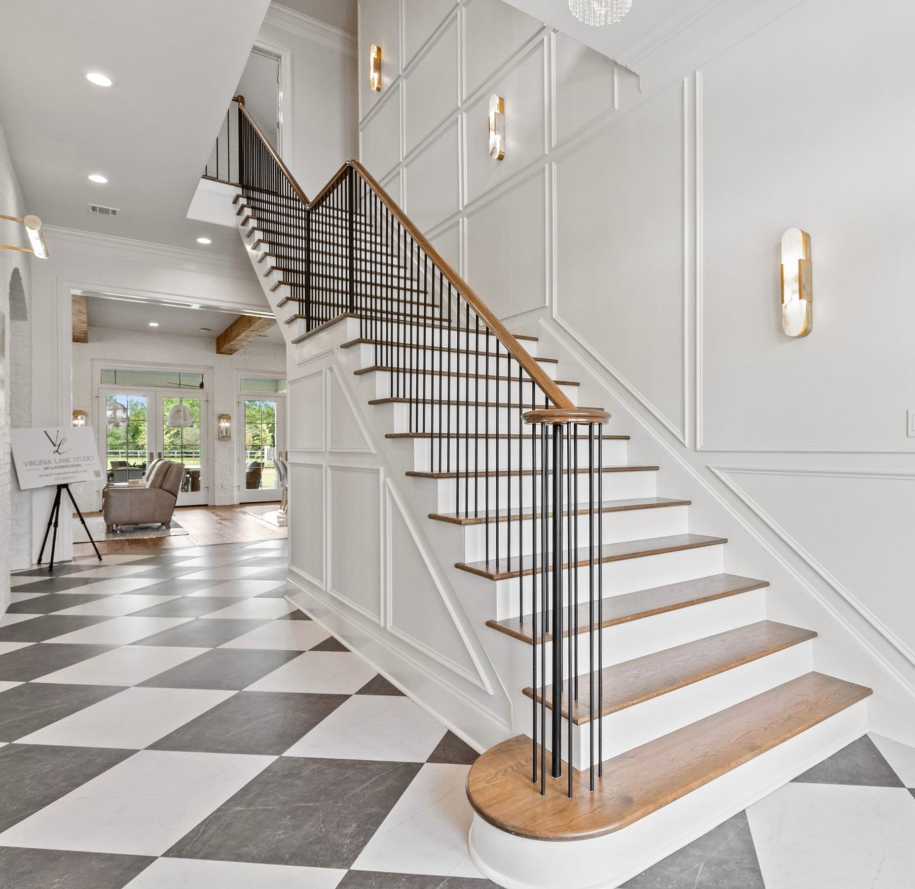 Bright foyer with black-and-white checkerboard floor and a white staircase with wooden treads