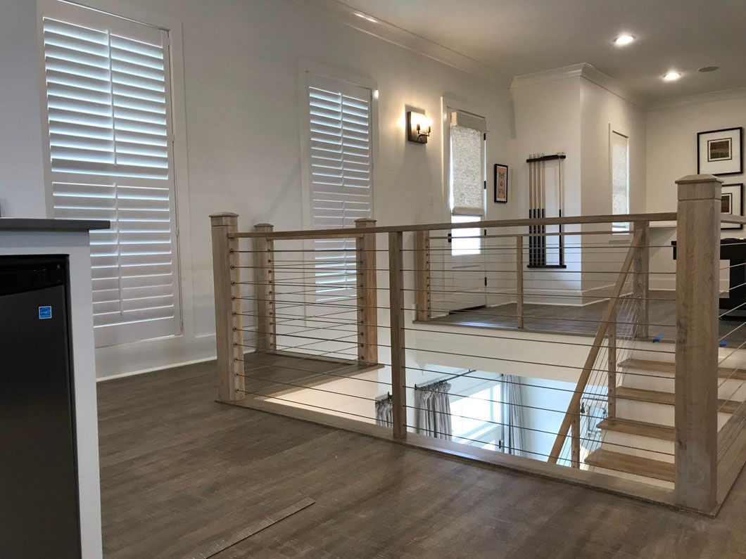 Bright modern hallway with wood floors and a glass-railed stair opening.