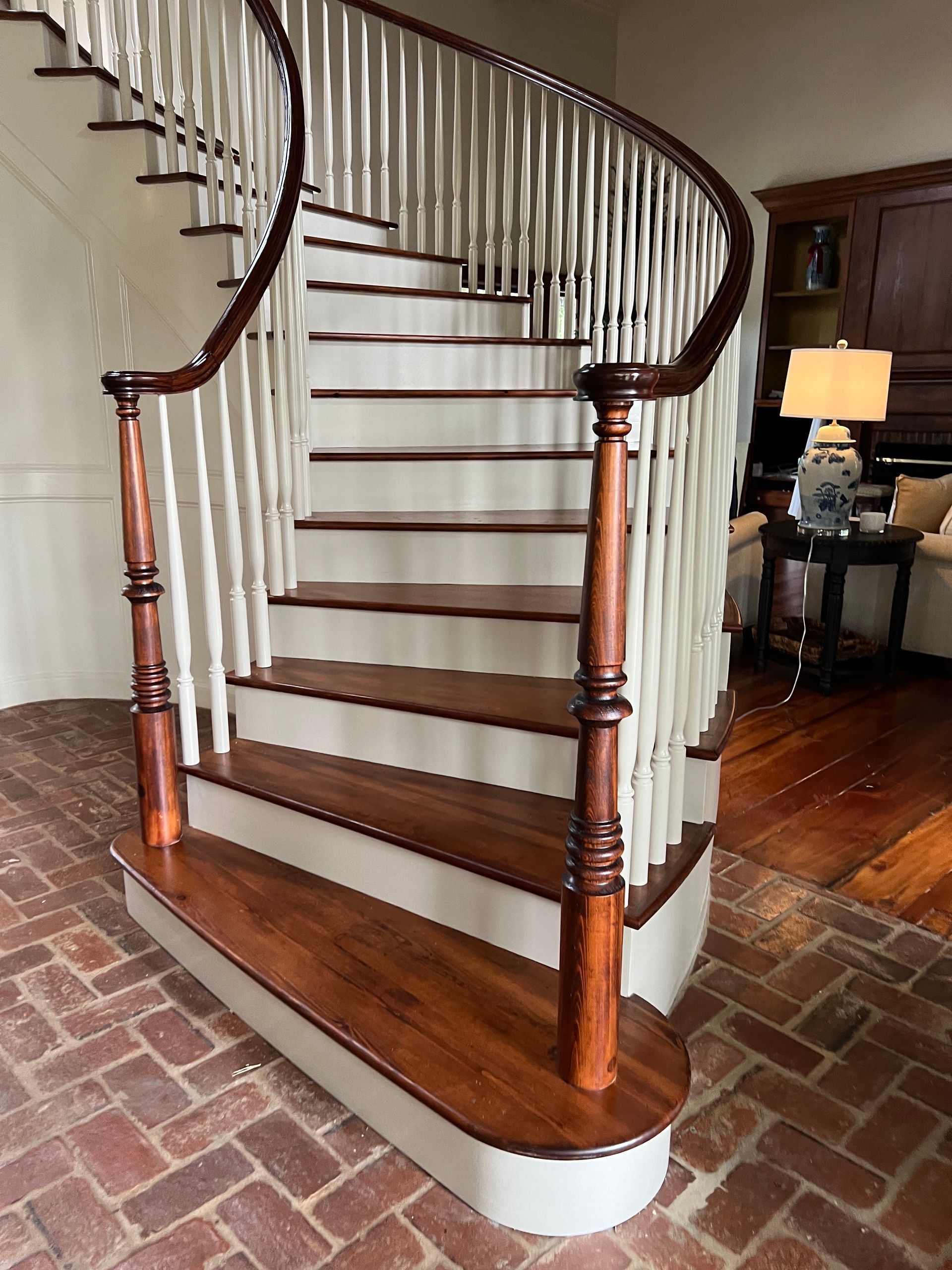 Curved wooden staircase with white risers and dark banister in a home interior.