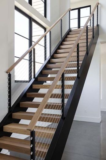 Indoor metal staircase with wooden steps and black railings in a bright modern building