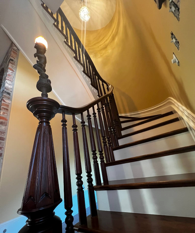 Elegant curved staircase with dark wood railing and yellow walls in a home interior