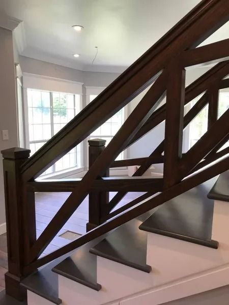 Wooden staircase with dark railing and white steps in a bright hallway