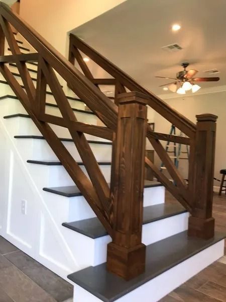 Wooden staircase with dark railings and white risers in a bright interior hallway