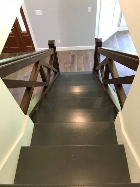 Top-down view of a dark stairway with wooden railings and tiled landing below