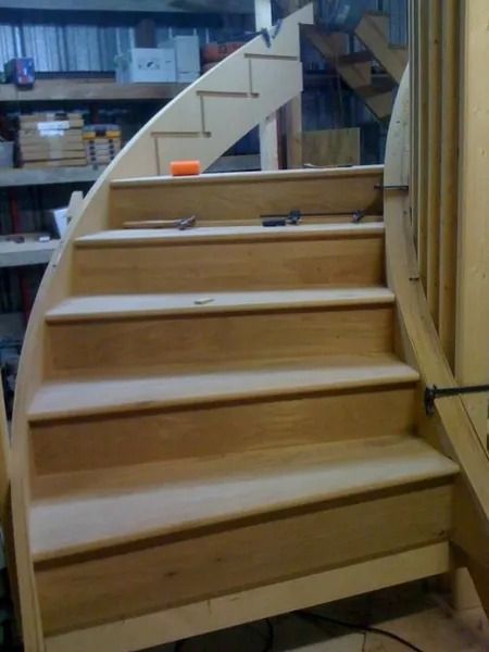 Unfinished wooden staircase in a workshop, with a small orange object on a step.