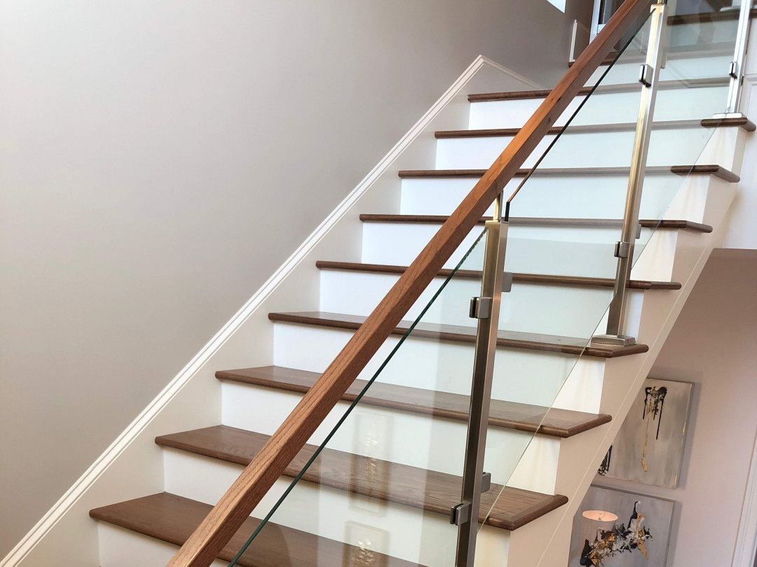 Modern indoor staircase with wood steps, black railings, and a glass side wall in a contemporary building