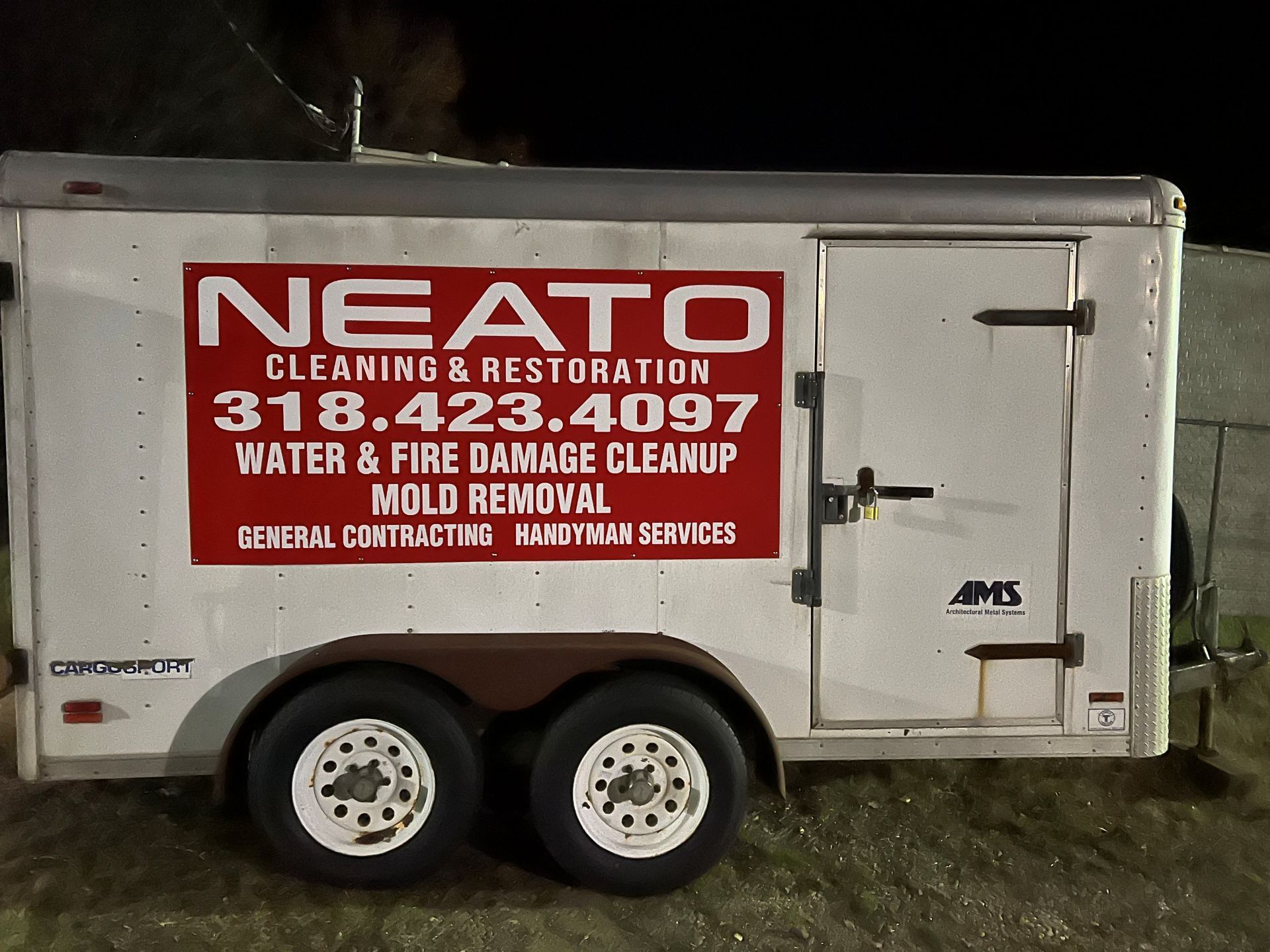 White rental truck with cleaning/restoration company signage parked outdoors on a gravel lot.