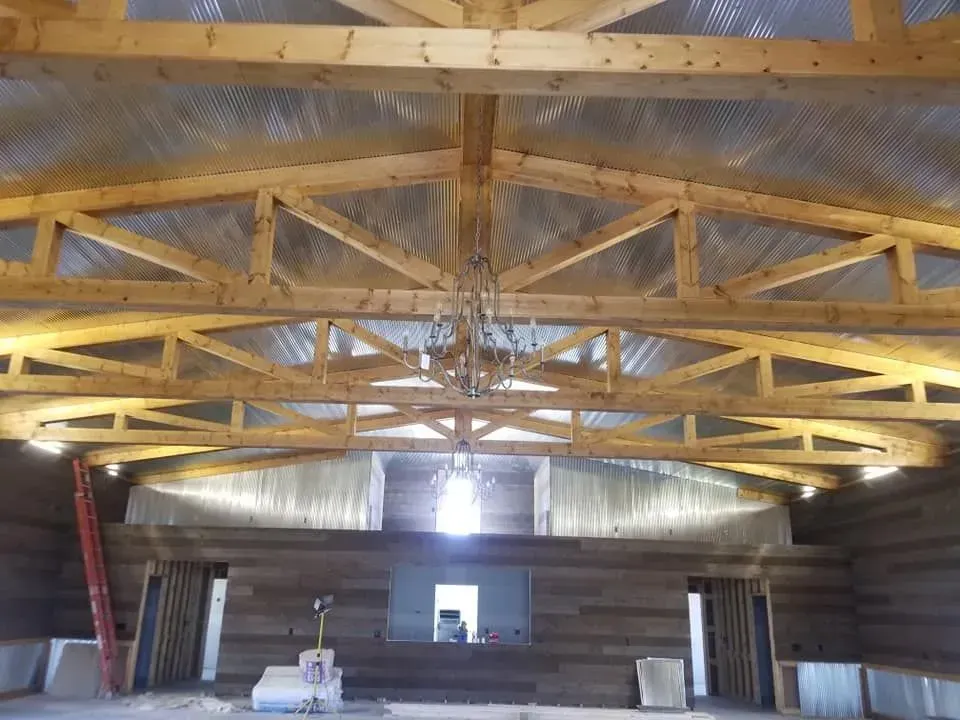 Wooden rafters and trusses of a building under construction with a light fixture in the center.