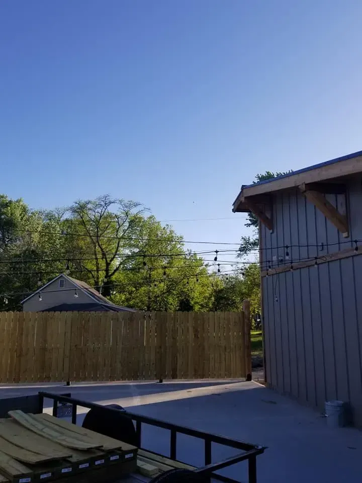 A partially visible outdoor space with a bamboo fence, building, and a clear blue sky.