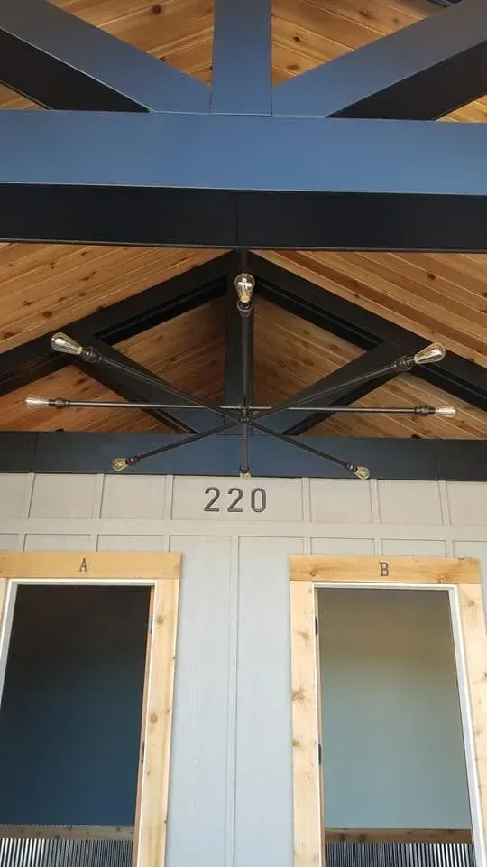 Black metal chandelier with Edison bulbs, above a door with the number 220.