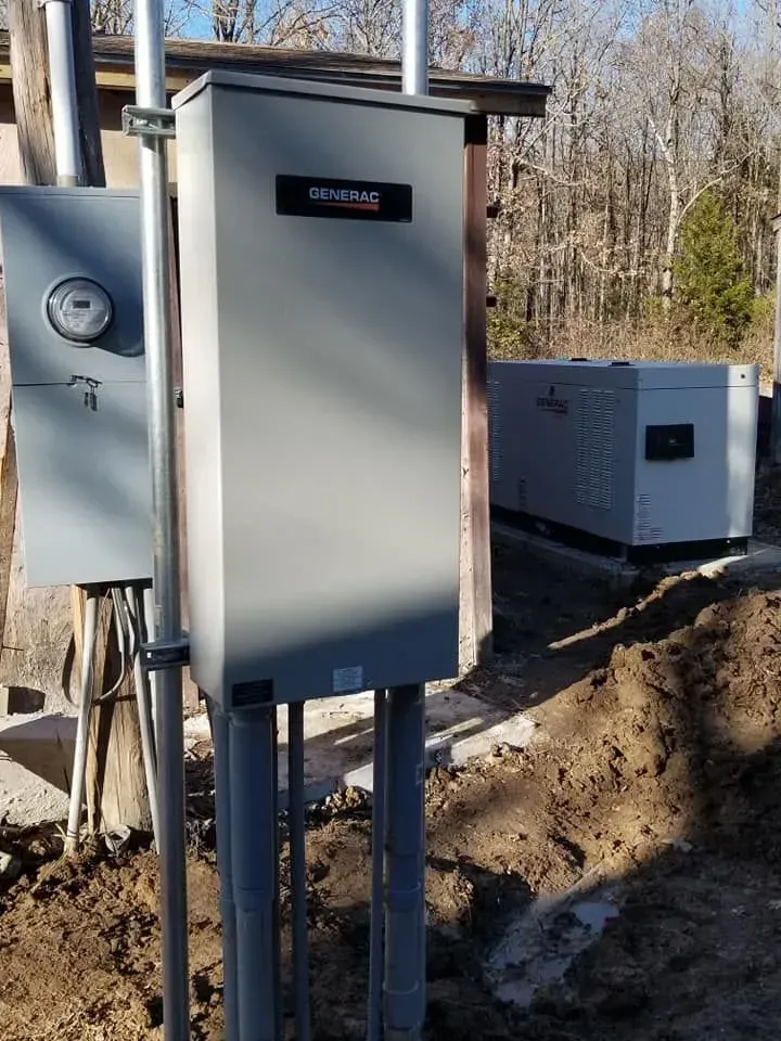 Electrical panel and generator outside a building, gray and silver.