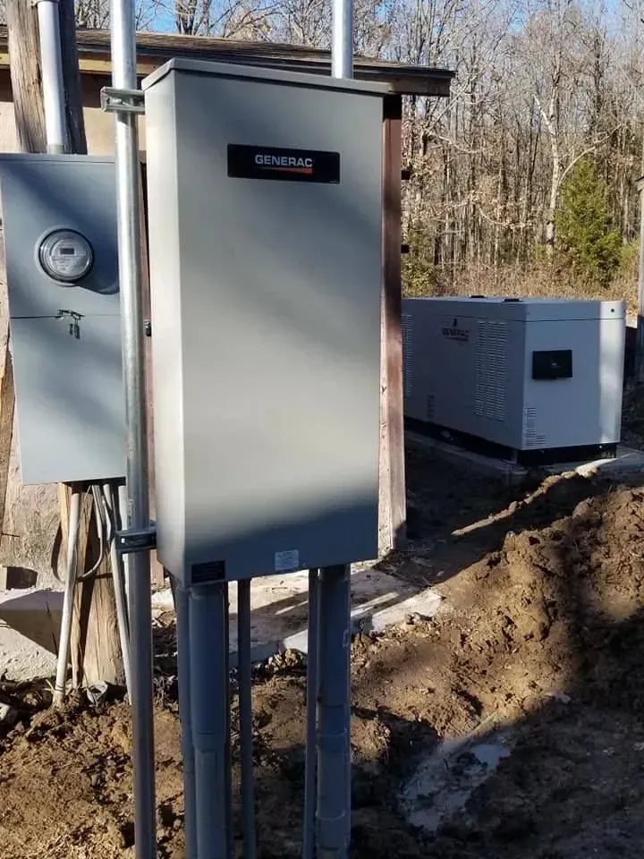 Gray Generac electrical panel, with conduit pipes, meter, and backup generator, outdoors.